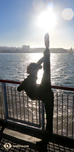Damit sie vom sonnendurchfluteten Anblick des Wassers nicht die Schau gestohlen bekommt, zeigt die Tänzerin Yiran Wang ihre Kunstfertigkeiten. Blick von Fisherman’s Wharf in San Francisco.